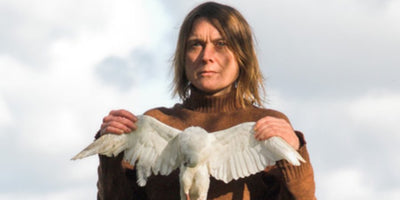 sarah lucas interview portrait woman sitting against white background with colorful artwork behind her