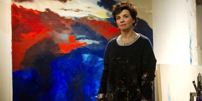 Juliette Binoche portrait smiling wearing black outfit against neutral background