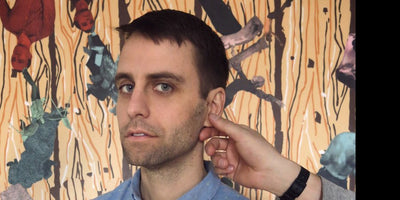 Performance artist Ryan McNamara posing in front of artwork at his new gallery show