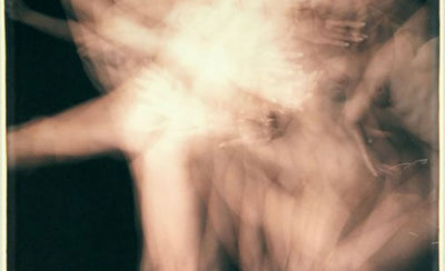 Polaroid instant camera with a collection of vintage polaroid photos on a wooden surface