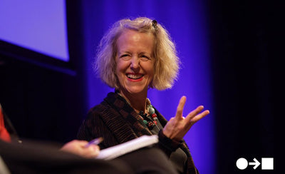 Barbara London discussing the early days of video art with a vintage video camera in an art gallery setting