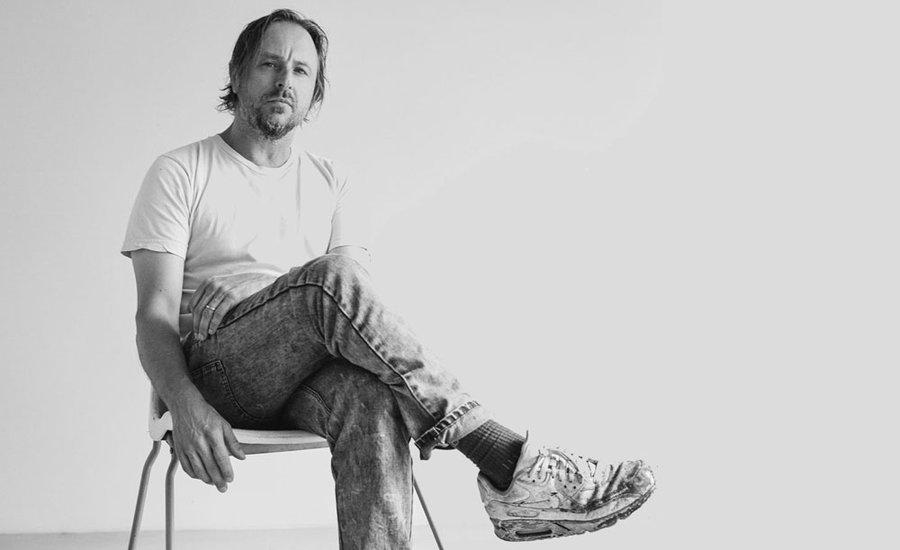 Interview with artist Sterling Ruby displayed on a digital screen with abstract artwork in the background