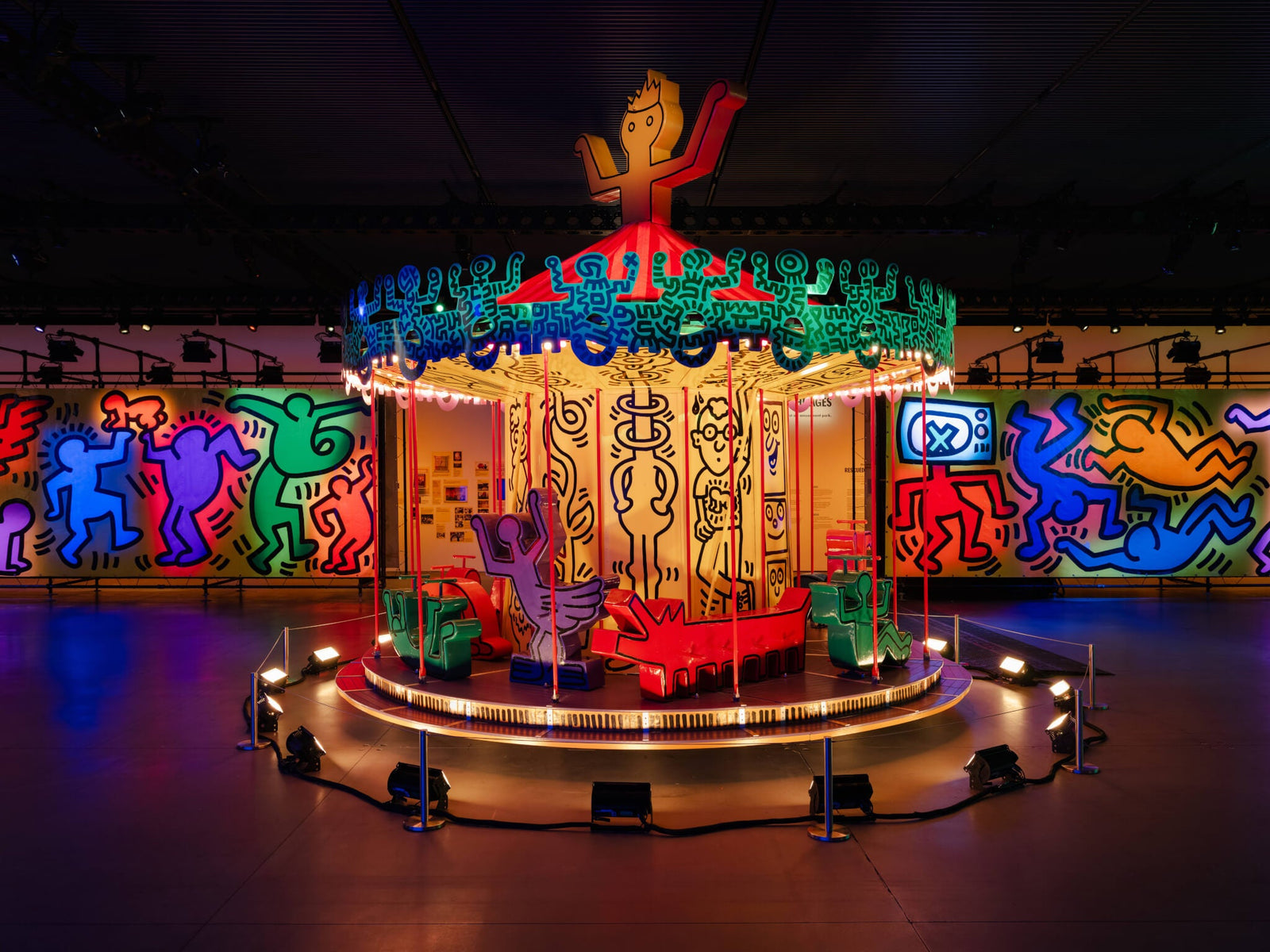 colorful carousel installation surrounded by vibrant Keith Haring inspired murals in an art exhibition hall, illuminated lighting enhancing the dynamic atmosphere