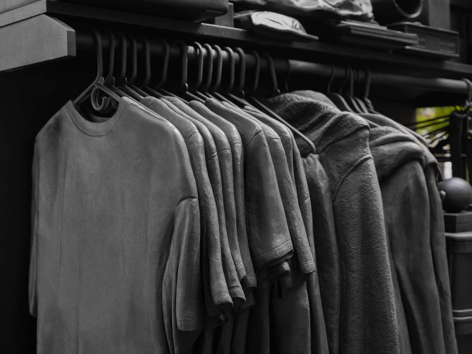 clothing rack featuring a selection of gray T-shirts and hoodies hanging in a minimalist display