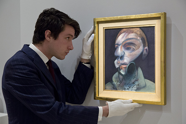 A Sotheby's employee with Francis Bacon, Self-Portrait, 1975,  oil on canvas, 35.5 by 30.5cm, est. £10-15 million. Image courtesy of Sotheby’s