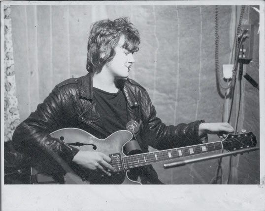 Stephen Harris tuning his Epiphone guitar in 1976