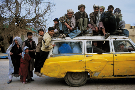 Steve McCurry, People sitting on and crowding inside a taxi, Mazar e sharif (2003)