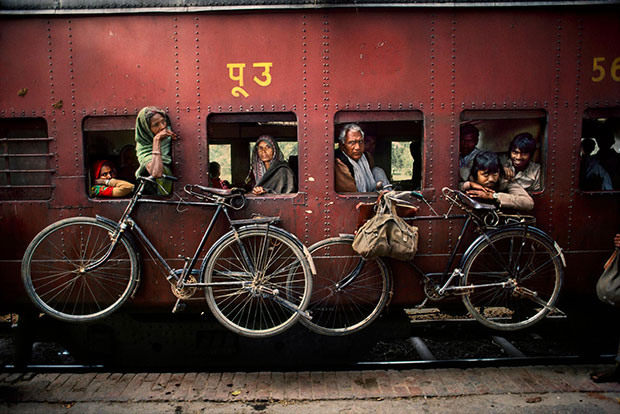 Bicycles hang on the side of a train, West Bengal (1983) by Steve McCurry. From Steve McCurry: India