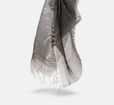 lightweight black and white scarf with fringed edges hanging against a plain background