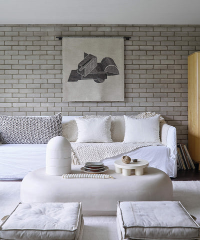 modern living room with white sofa, textured pillows, abstract wall art, and minimalist coffee table