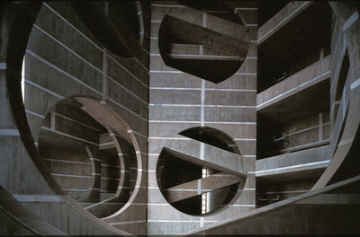 interior view of modern architectural design featuring abstract circular shapes and concrete surfaces with natural light streaming through openings