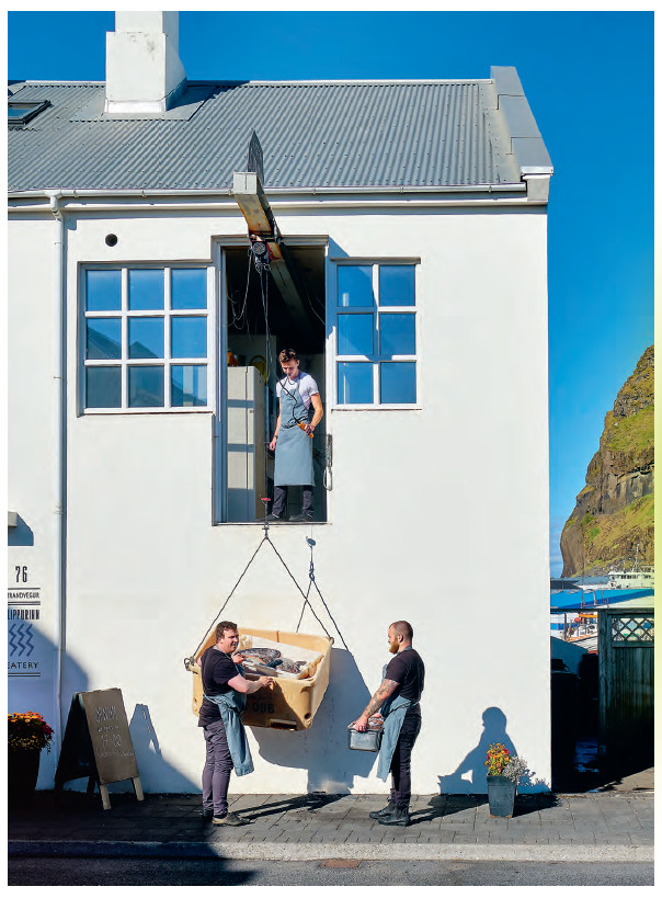 Chef Gísli Matt (bottom right) inspects the fish being loaded into Slippurinn
