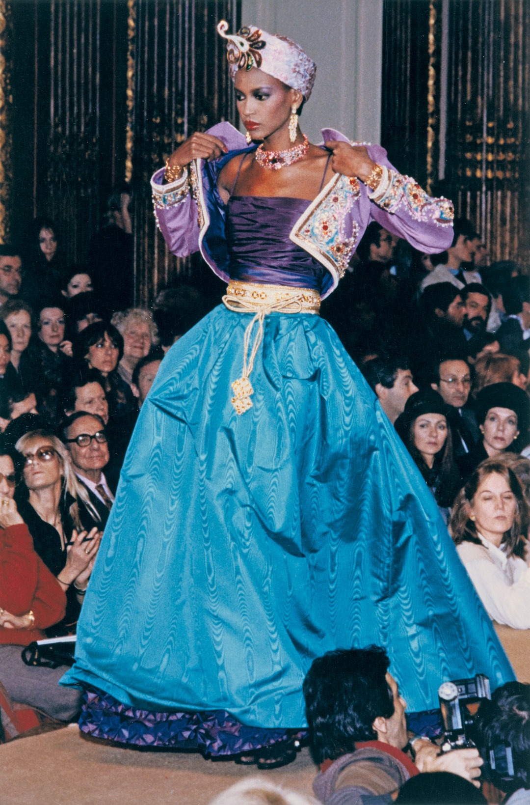 Pleated lamé turban ornamented with a sequined palm leaf created by Nina Wood, gold braid belt embroidered with pearls (made by Leroux), worn with an Indian-inspired evening outfit, Spring/Summer 1982 haute couture collection. © Fondation Pierre Bergé – Yves Saint Laurent, Paris/All Rights Reserved