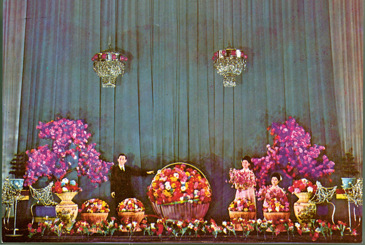 A magician performs his best floral tricks in this postcard