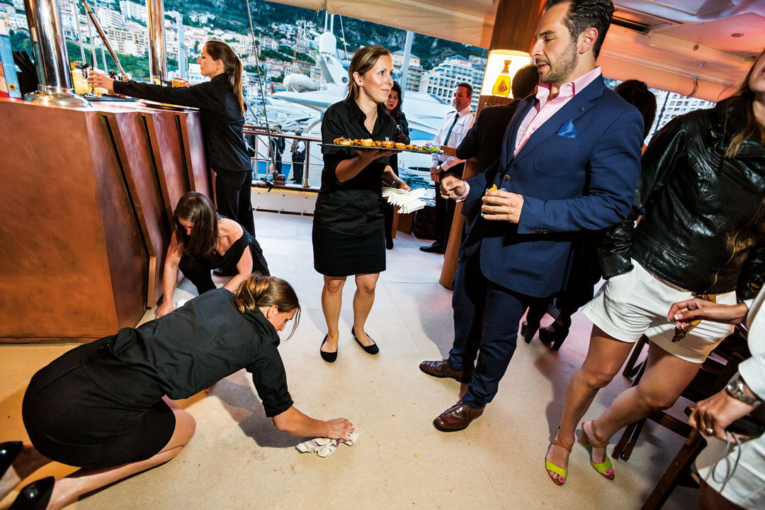 A waitress cleans up a spill at a party hosted by whiskey maker Johnnie Walker on its branded, 157-foot yacht during the Monaco Grand Prix, Monte Carlo, 2013.