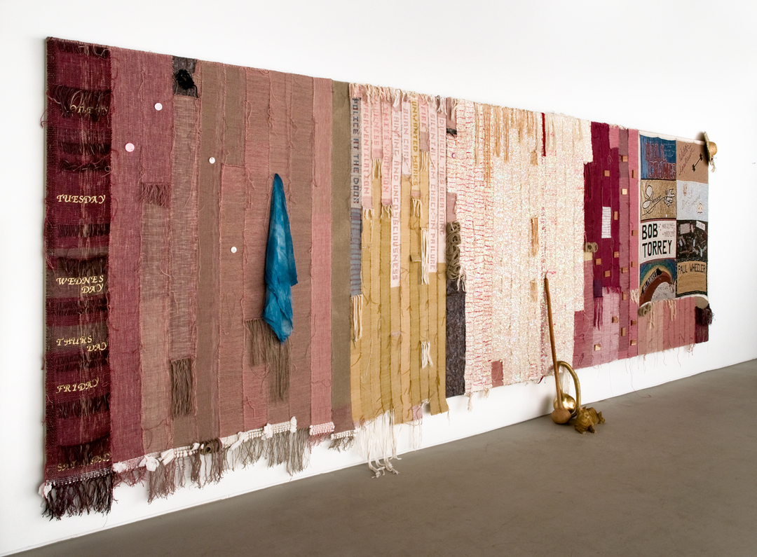 Josh Faught, It Takes a Lifetime to Get Exactly Where You Are, 2012, handwoven sequin trim, handwoven hemp, cedar blocks, cotton, polyester, wool, cochineal dye (made from ground up bugs), straw hat with lace, toilet paper, paper towels, scrapbooking letters, Jacquard woven reproduction of a panel from the AIDS quilt, silk handkerchief, indigo, political pins, disaster blanket, gourd, gold leaf, plaster cats, cedar blocks and nail polish, 244 × 609.5 cm, Collection, Saatchi Gallery, London. Photo: Cary Whittier
