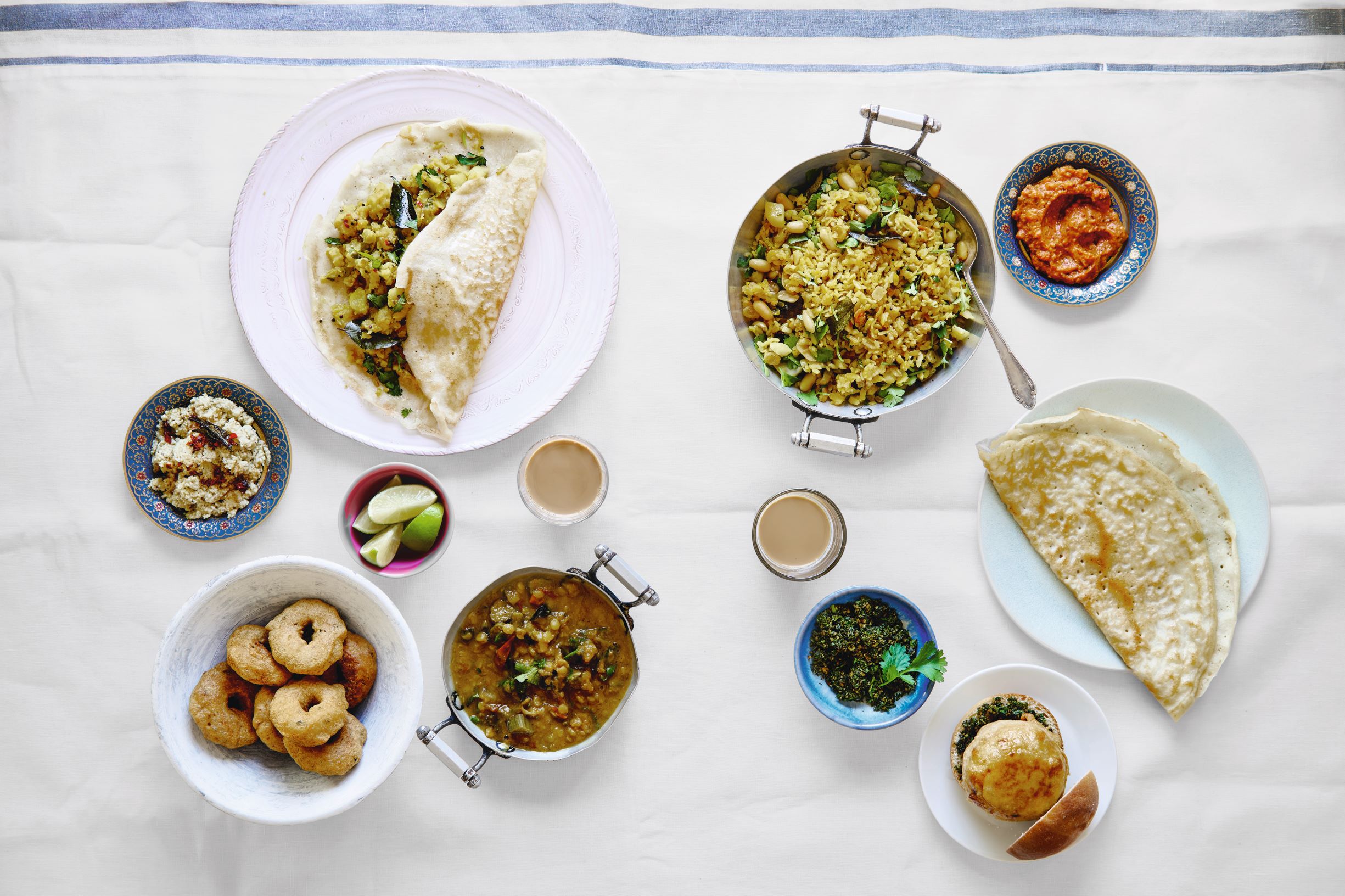 Clockwise from top left: dosa with aloo masala; flattened rice porridge; tomato chutney; chai karak; dosa; fried potato sandwich; coriander chutney; sambar; spiced lentil fritter; coconut chutney; from the Indian pages of Breakfast: The Cookbook