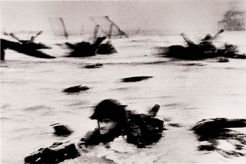 The first wave of American troops landing on D-Day,Omaha Beach, Normandy Coast, France, 6 June 1944 by Robert Capa. As reproduced in our Robert Capa book and in Magnum Stories