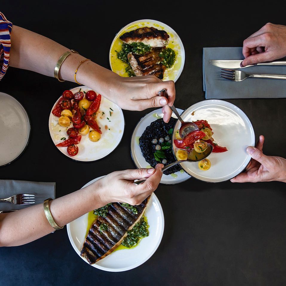 Wild caught trout, grilled cod, black venere rice and white currants, tomato salad, courtesy of Studio Olafur Eliasson Kitchen's Instagram account