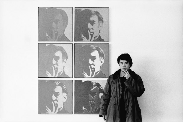 Ai Weiwei at the Museum of Modern Art in New York, 1987, beside Andy Warhol's Self Portrait (1967). Courtesy of Andy Warhol | Ai Weiwei, NGV International, Melbourne, Australia