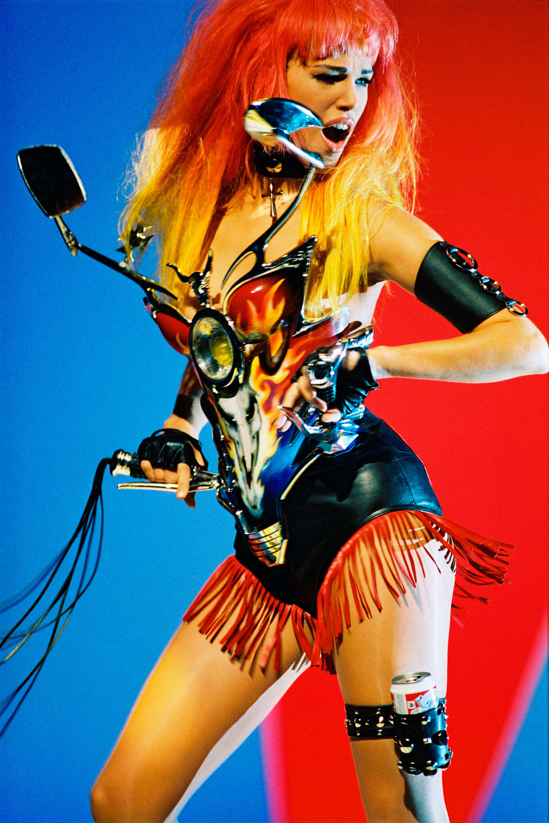 Patrice Stable, Model Emma Sjöberg Wiklund on the Set of George Michael’s Too Funky Video Shoot, Paris, 1992. Outfit: Thierry Mugler: Les Cow-boys collection, prêt-à-porter  spring/summer 1992. “Motorcyle-fairing” bustier of hand- painted Plexiglas (Jean-Jacques Urcun), padded heart on the back. Fringed leather shorts. Matching “Budweiser” garter. Photo: © Patrice Stable.