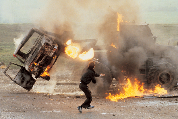 Petrol bombs thrown by Catholics in Belfast destroy a British armoured car, 1981. Photograph by James Nachtwey. As featured in Century