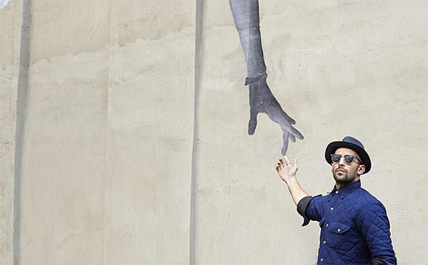 JR with one of his pasted-up public art works, Manhattan, 2015
