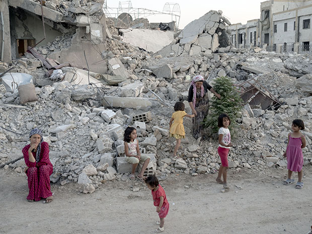 A family stands on what is left of their home. SYRIA. Kobani / Kobane (Arabic: Ayn al Arab). 06 August 2015. © Lorenzo Meloni/Magnum Photos