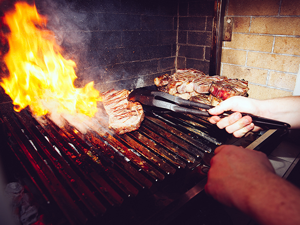 Magnus prepares the steak at Adam Sachs’ Brooklyn house. Photograph by Michelle Heimerman