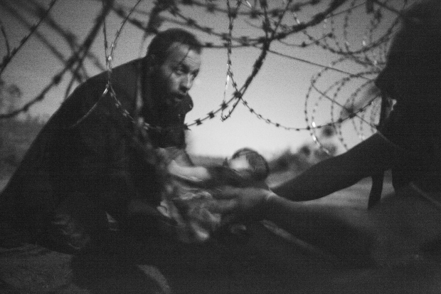 World Press Photo of the Year. Warren Richardson, Australia, 2015, Hope for a New Life. A man passes a baby through the fence at the Serbia/Hungary border in Röszke, Hungary, 28 August 2015.